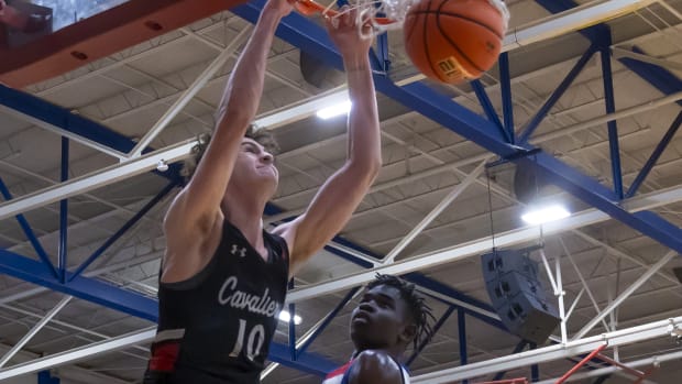 Lake Travis Cavaliers forward Hudson Greer (10) slam dunks and hangs on the rim as Westlake Chaparrals center Wonder Kahozi (35) looks on during the second period at the District 26-6A boys basketball game on Tuesday, Dec 5, 2023, at Westlake High School West Lake Hills, TX.