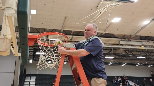 Magnificat head coach Danny Gallagher cuts down the net after the Blue Streaks defeated Medina in a regional final on March 9, 2024.