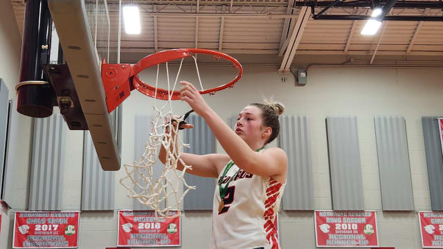 Loudonville's Corri Vermilya cuts down the net after the Redbirds won the Division IV district title over Mogadore on March 2, 2024