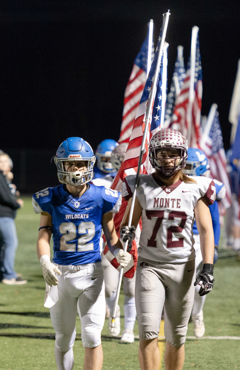 La Center's Levi Giles and Montesano's John Southard jointly carry an American flag off the field following a pregame tribute to the tropps before a 1A Southwest District playoff game on Friday, Nov. 5, 2021, at Beaver Stadium in Woodland. Montesano won 42-20. (Joshua Hart/For ScorebookLive)