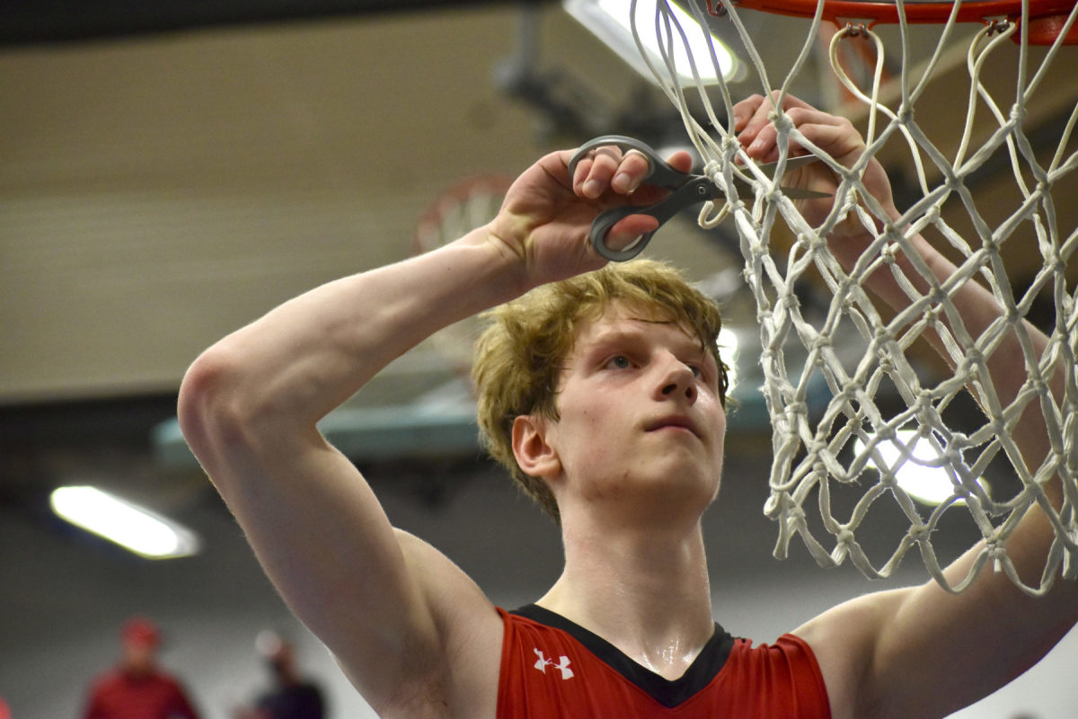 R.A. Long forward Aaron Ofstun cuts down the net after a district title win over Tumwater on Feb. 18.