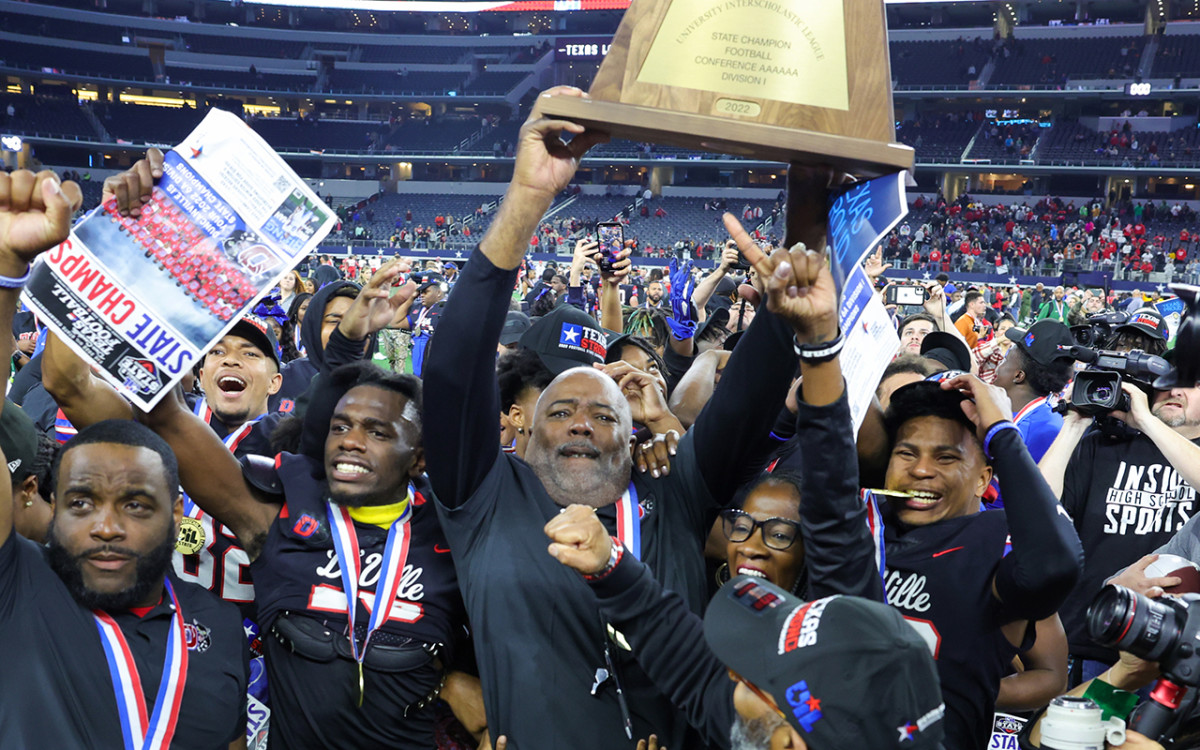 Duncanville head coach Reginald Samples holds up a UIL Class 6A Division I state championship trophy in December 2022.