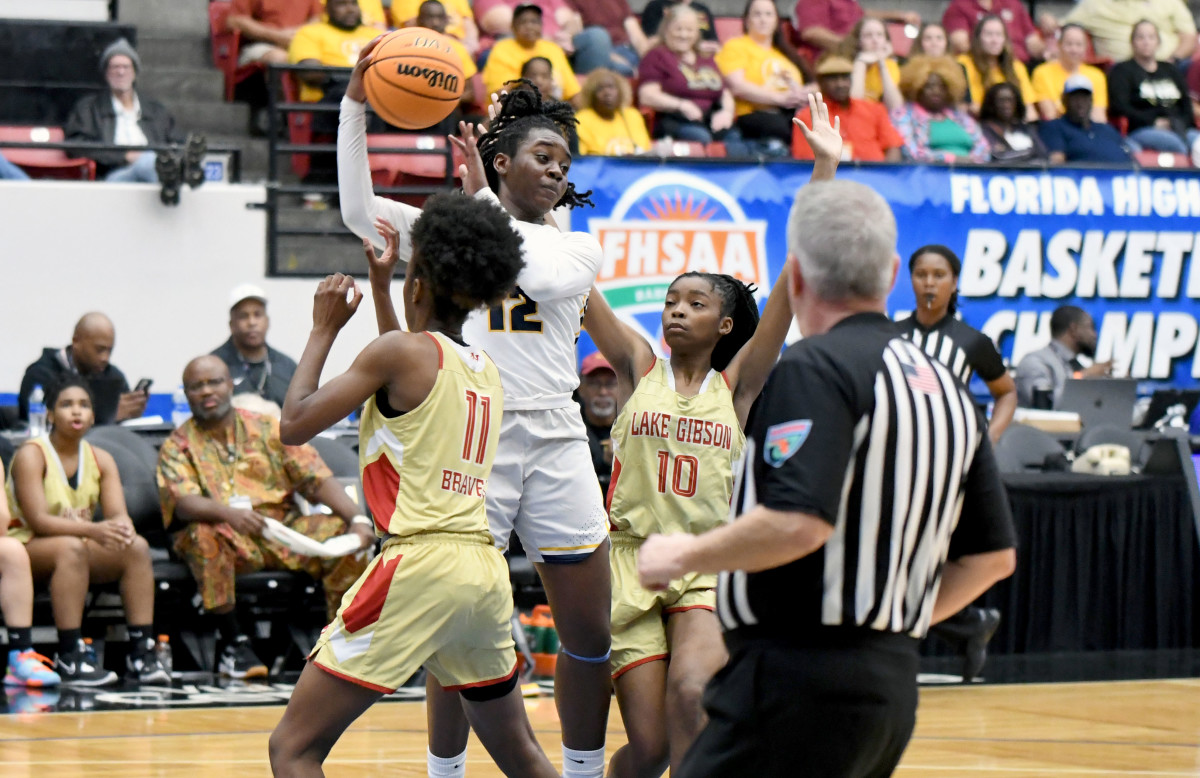 St. Thomas Aquinas guard Reina Green (12) looks for help from a teammate while Lake Gibson defenders Taleah Turner (10) and Jamila Ray (11) close in on defense at the FHSAA Class 6A girls basketball state semifinals on Thursday at the RP Funding Center in Lakeland.