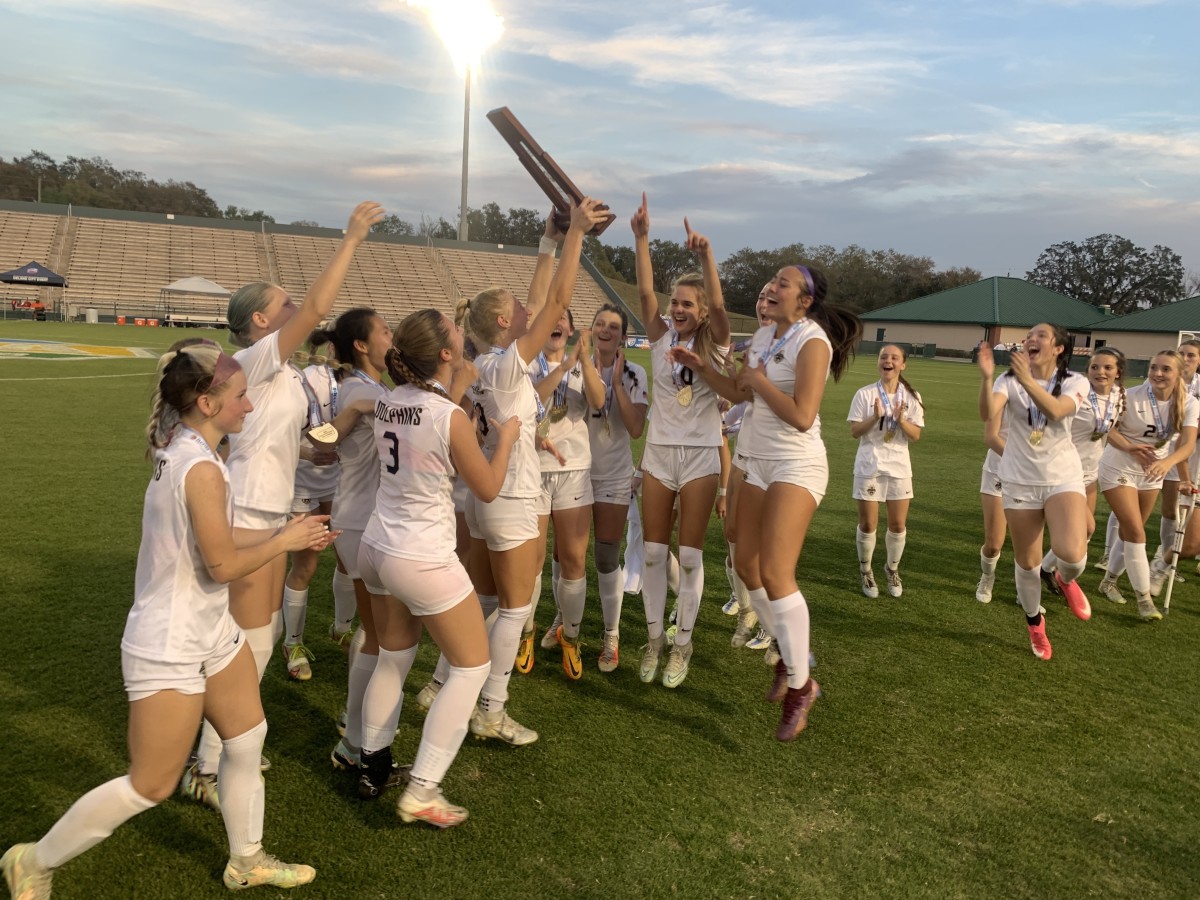 Ava Matherne brings the state-championship trophy to her Gulf Breeze teammates after their 4-1 victory over Lourdes in the 6A state girls soccer final.