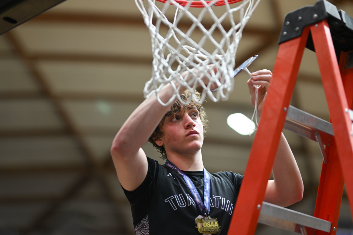 Tualatin forward Jaden Steppe cuts down the net after helping Tualatin win its second consecutive OSAA Class 6A state title in March 2023.