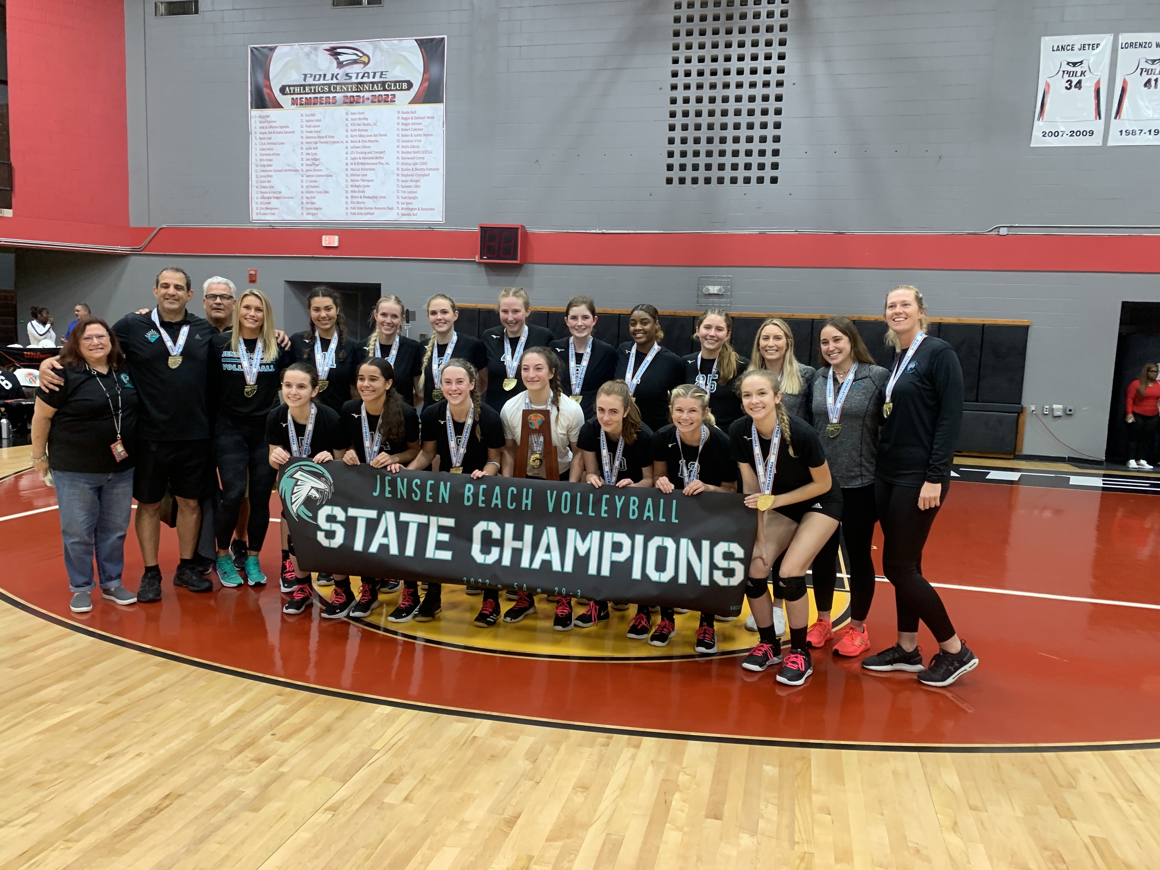 Jensen Beach stands with the state-championship trophy and a banner to match after the Falcons' 25-17 25-15 25-22 victory over Naples Barron Collier in the FHSAA Class 5A volleyball final.