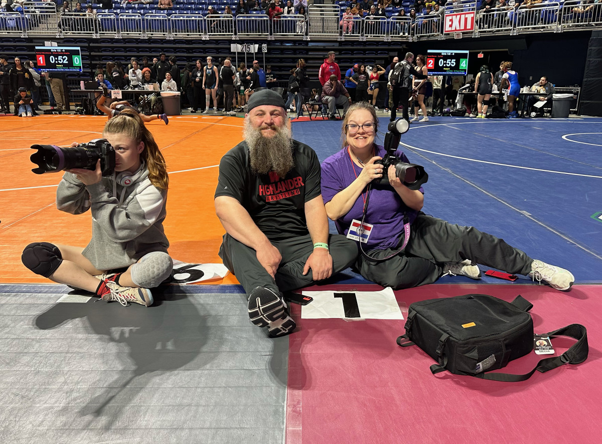 Riley Rayome (left) takes photos during a tournament earlier this season as her father and The Woodlands wrestling coach Jeff Rayome and her mother Amanda sit on the mats. Photo by Carissa Mooney of Phlox Photography 