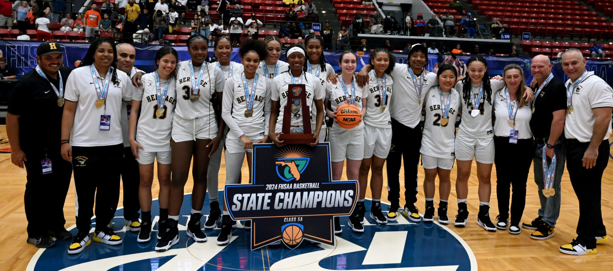 Plantation American Heritage girls basketball players and coaches gather around their trophy after winning the Class 5A state championship on Friday at the RP Funding Center in Lakeland.