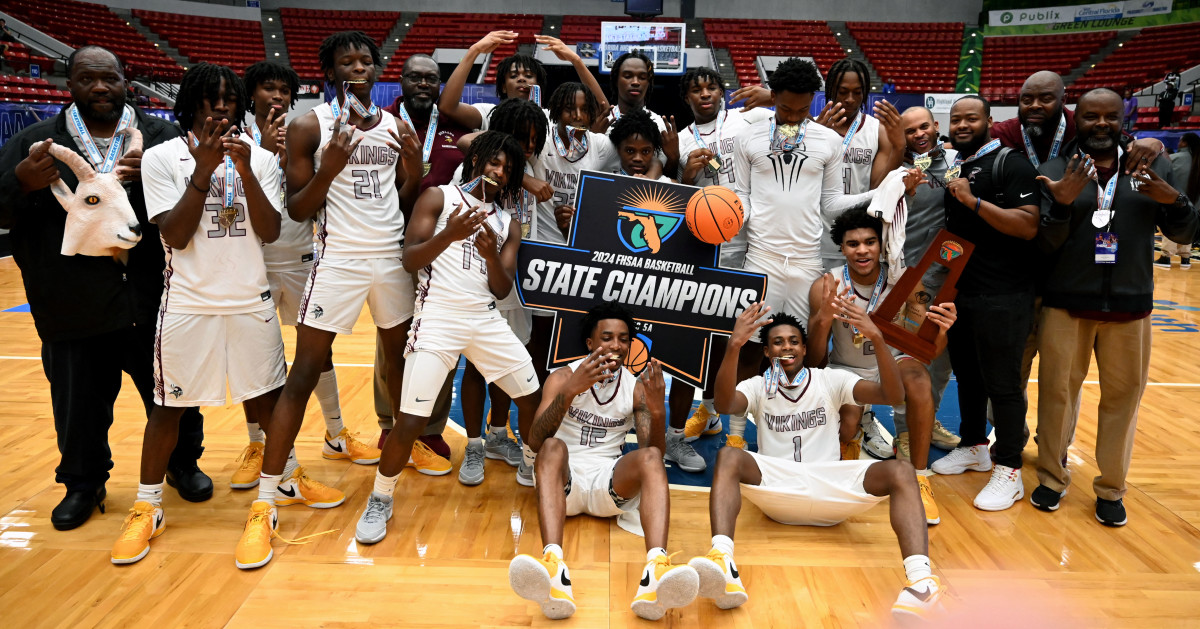 Miami Norland players and coaches gather around the  Class 5A state championship basketball trophy on Friday after beating Tampa Blake for the title at the RP Funding Center.