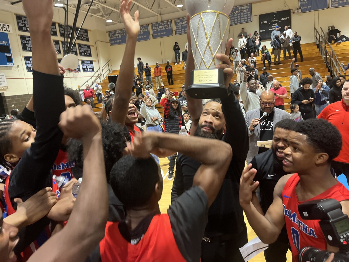 DeMatha head coach Michael G. Jones hoists the 2024 Maryland Private Schools State Tournament championship trophy as his team's celebrates its title after its championship game victory over top-seeded Bullis.
