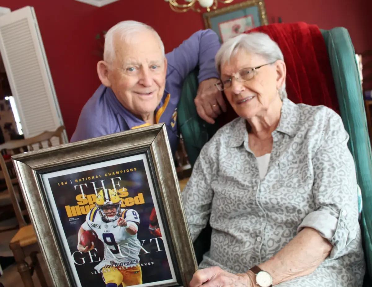 Dorothy "Dot" Ford and her husband John pose for a photo with a framed Sports Illustrated cover featuring their grandson, Heisman-winning LSU quarterback Joe Burrow.