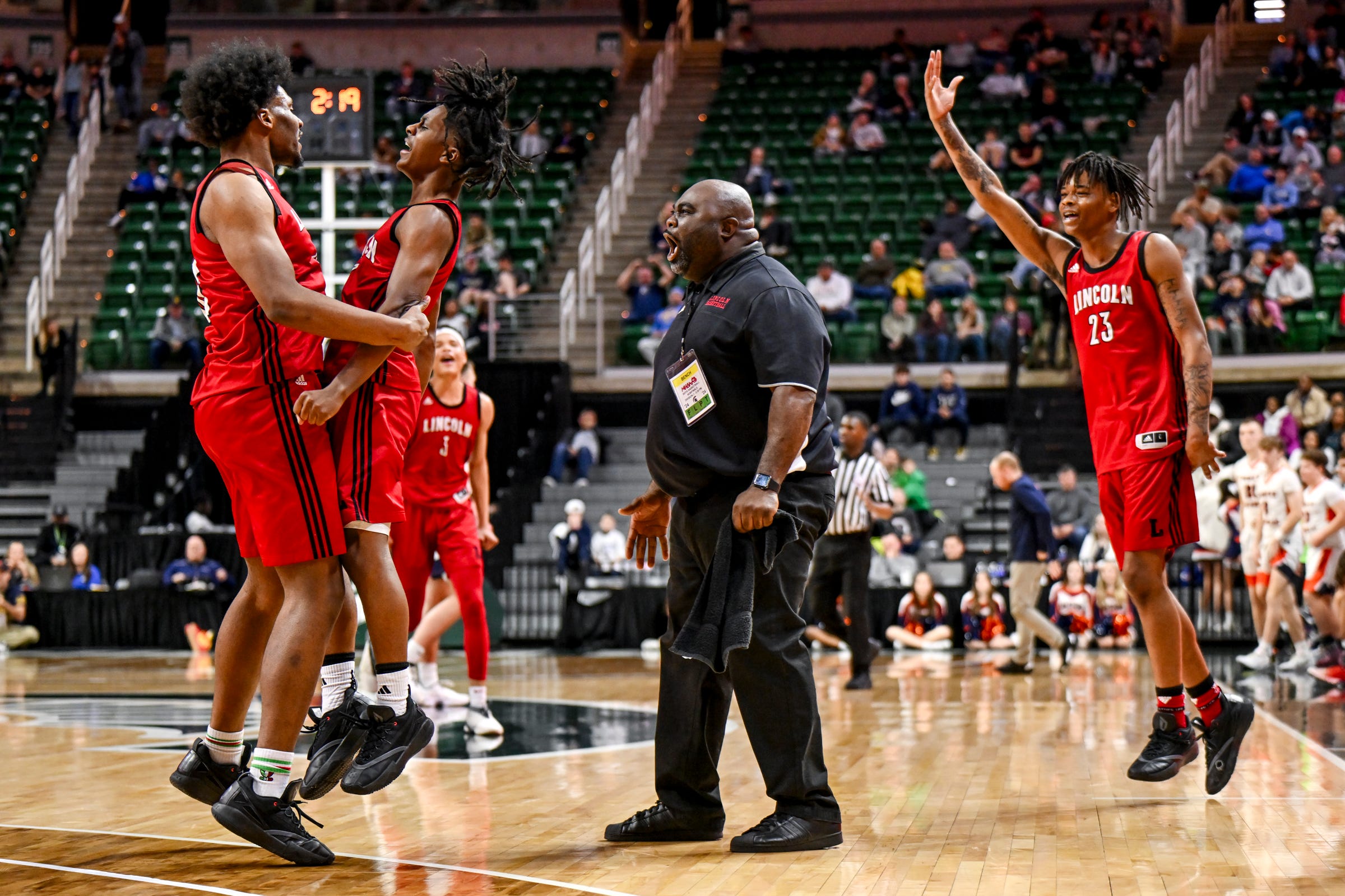 Warren Lincoln's Timarion Minor, Moses Blackwell, head coach Wydell Henry and Jamari Culliver celebrate after Minor's basket in a win over Flint Powers Catholic in the Michigan D2 boys basketball state semifinal on Friday.
