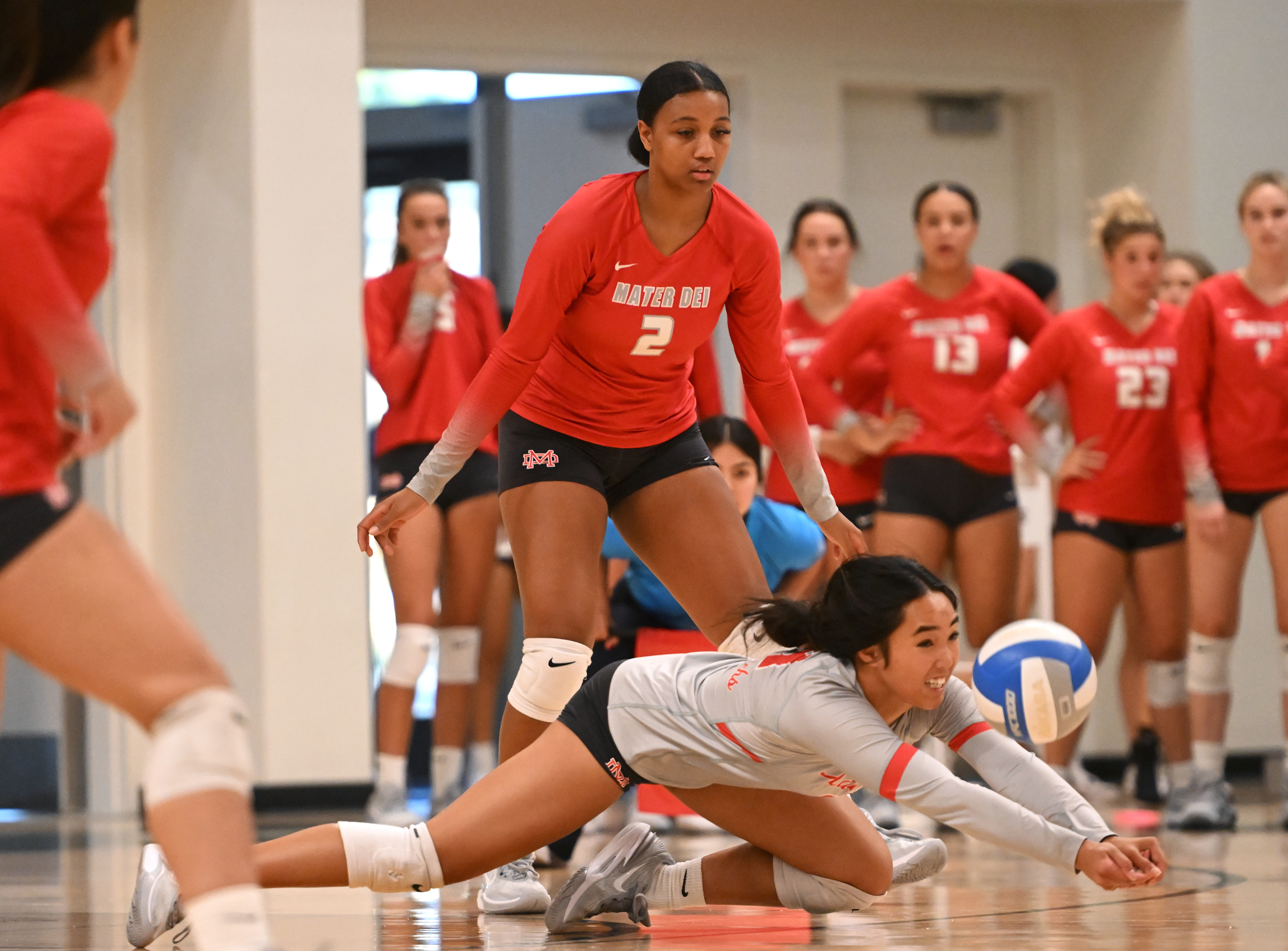 Mater Dei senior, Stanford-bound libero Malyssa Cawa dives for ball while  Isabel Clark (2) looks on