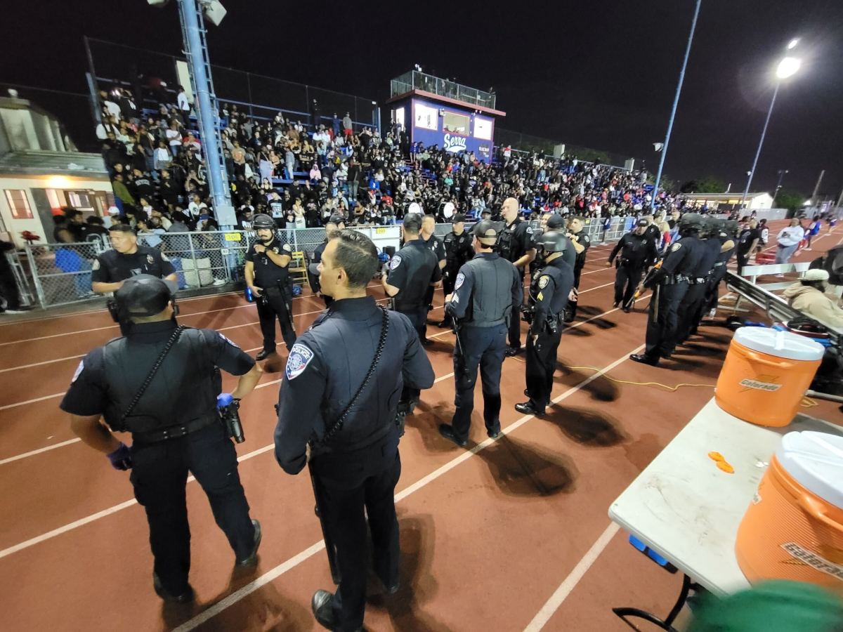 Police equipped with riot helmets prep for how to deal with the large, overwhelming crowd at Long Beach Poly vs. Serra football game in Gardena, Calif.