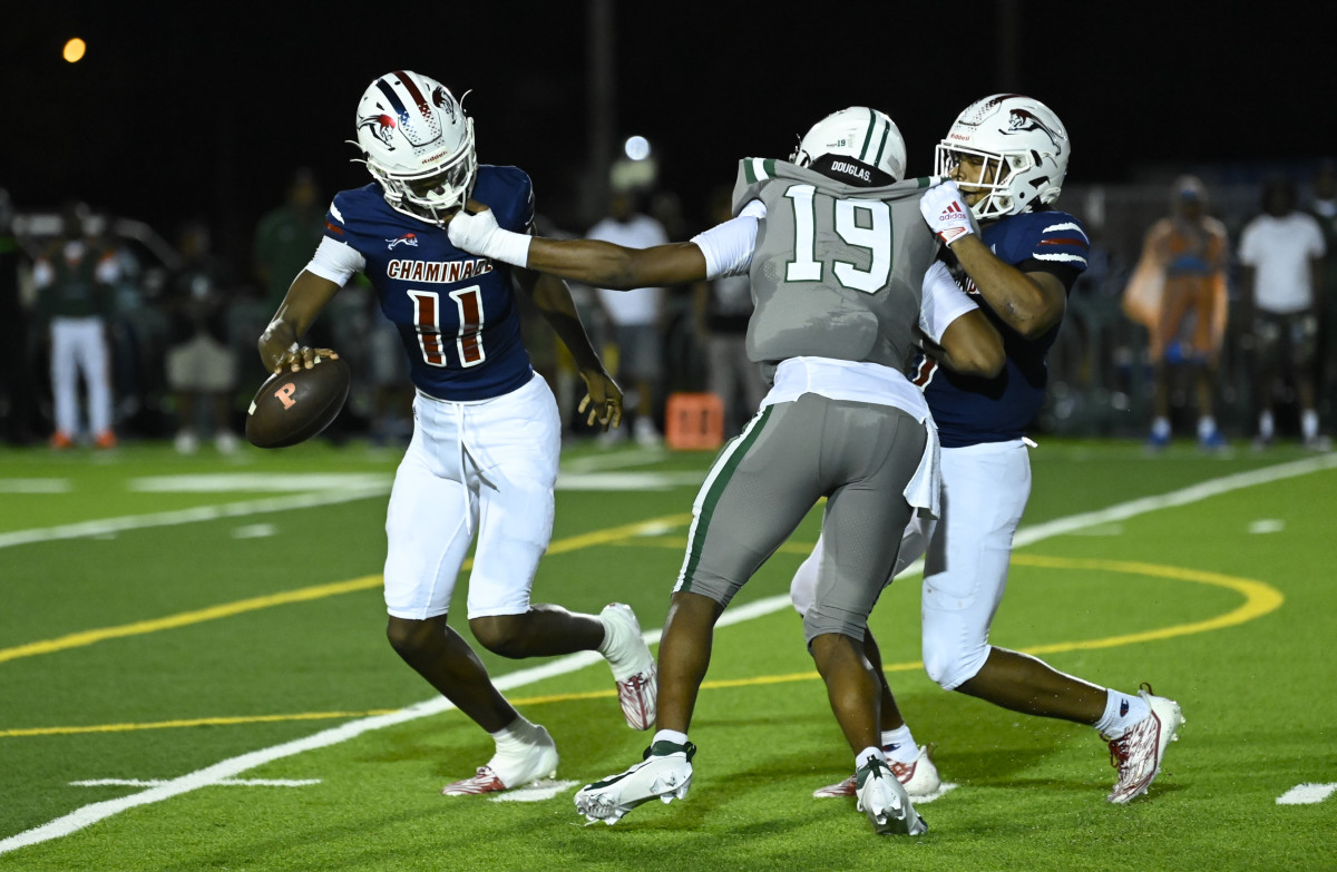 Chaminade-Madonna quarterback Cedrick Bailey (11) tries to avoid the pass rush of Miami Central's Deangelo Thompson (19).