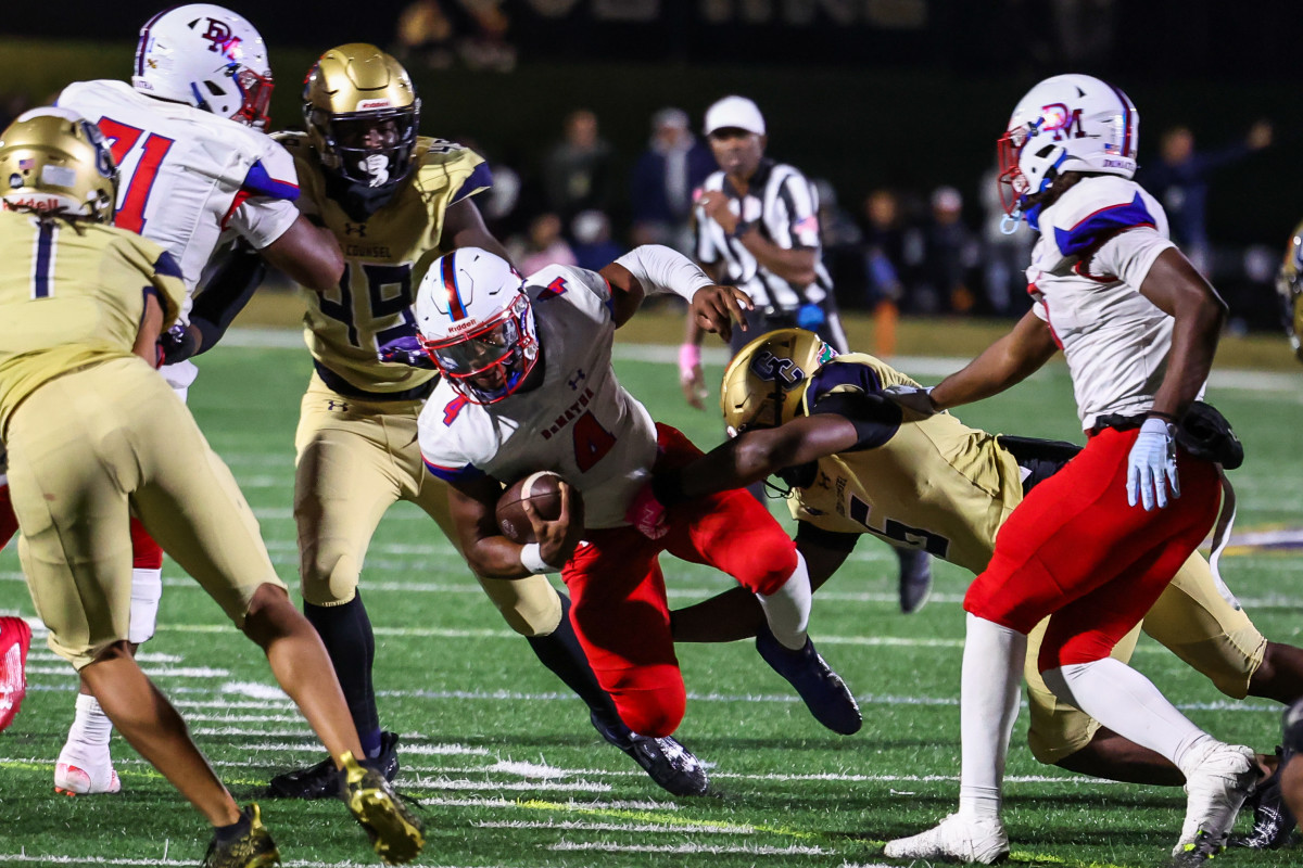DeMatha quarterback Denzel Gardner (4) tries to get through a hole as Good Counsel's Aaron Chiles closes in for a tackle. The Stags led for nearly the entire second half Friday evening before Good Counsel got a touchdown and tying 2-point conversion in the final seconds of regulation. The Falcons won in overtime.