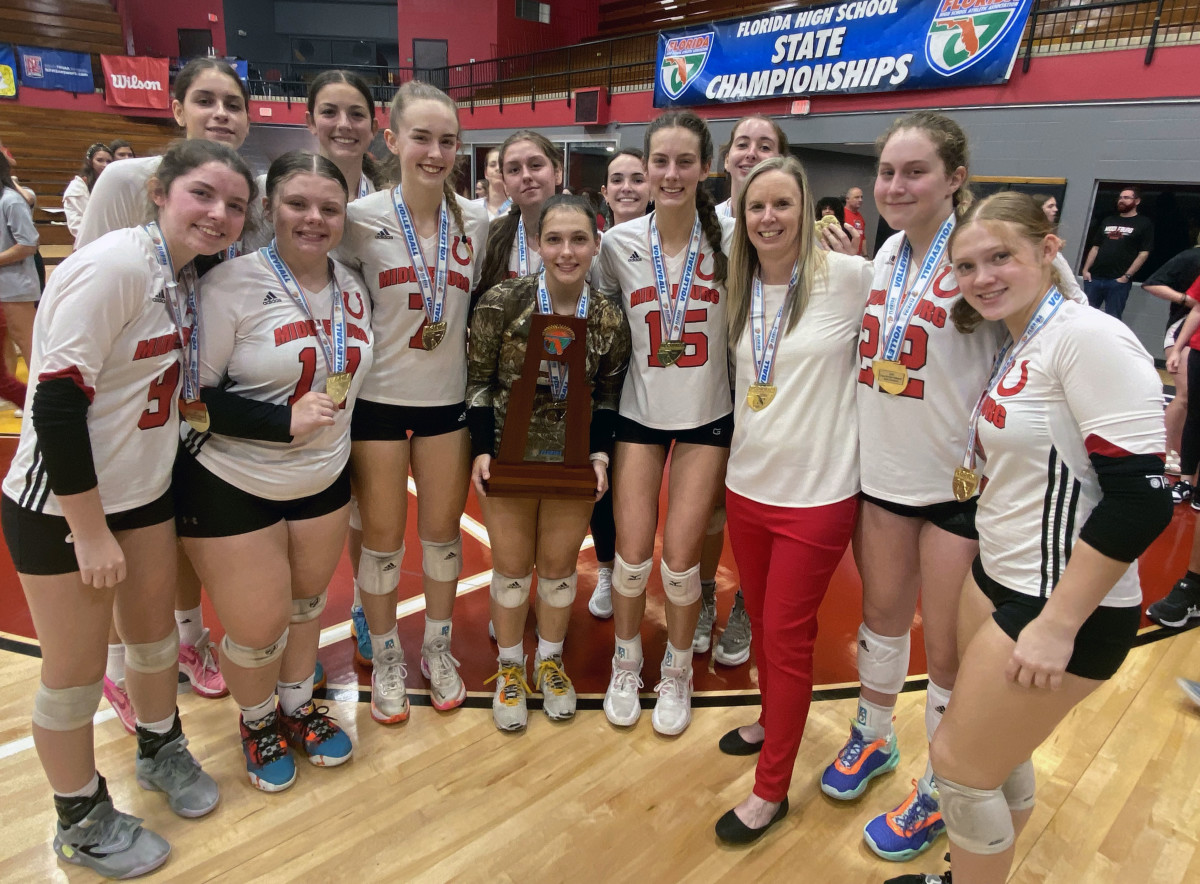 Middleburg players and head coach Meredith Forkum stand with their trophy after winning the FHSAA Class 5A girls volleyball state championship on Thursday at Polk State College in Winter Haven.