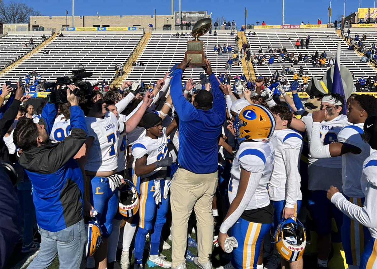 Loyola Blakefield head football coach Anthony Zehyou lifts the Turkey Bowl trophy up as his team gathers around, following the Dons' 40-28 victory over Calvert Hall in the 103rd Turkey Bowl, Thursday morning at Towson University's Johnny Unitas Stadium.