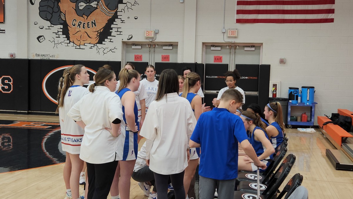 Lake girls basketball head coach Ashley Phipps-Komo (hands on hips) watches as her assistant coaches lead the huddle in a game against Green on January 27, 2024